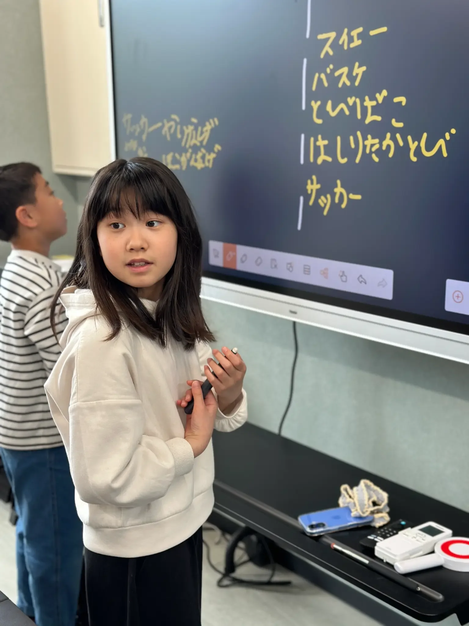 電子黒板の前でペンを持って振り返る子ども