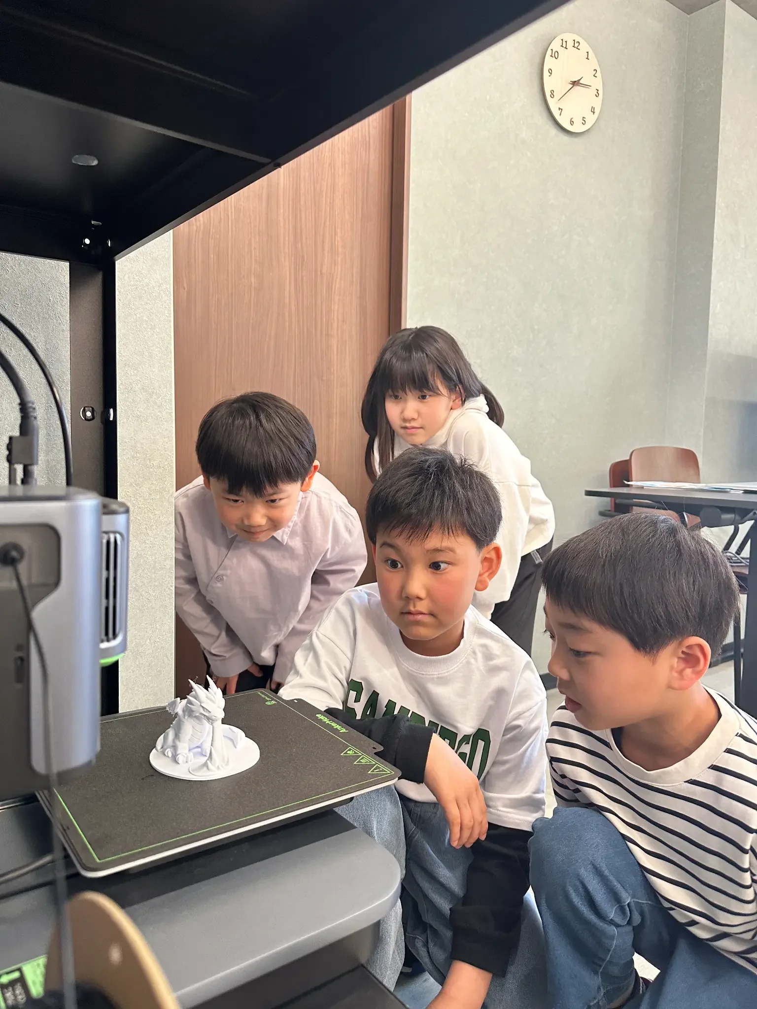 3Dプリンターで完成した作品をのぞき込む子どもたち