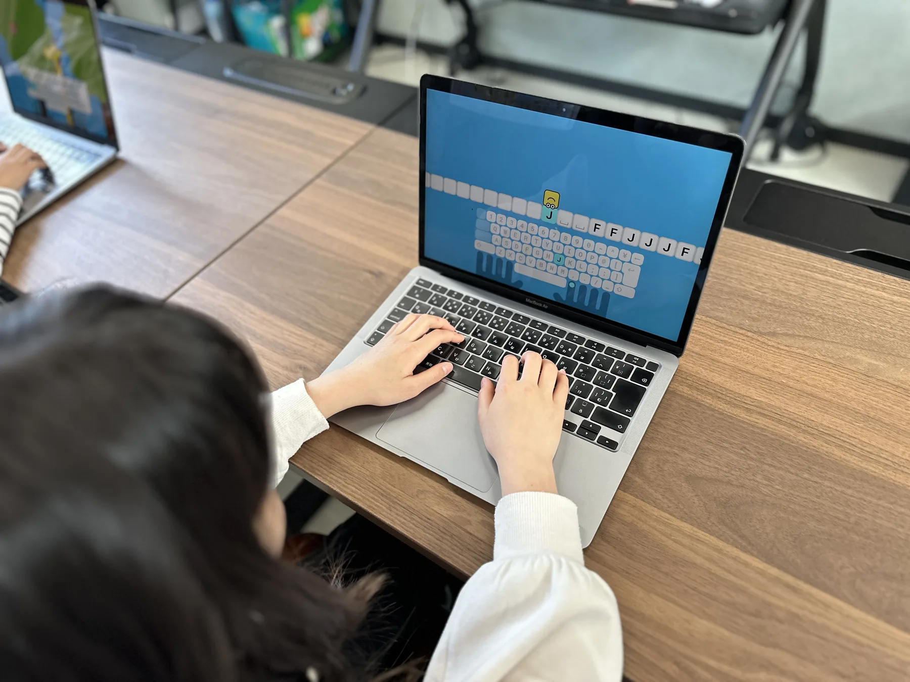 ノートパソコンでタイピングする子どもの手元